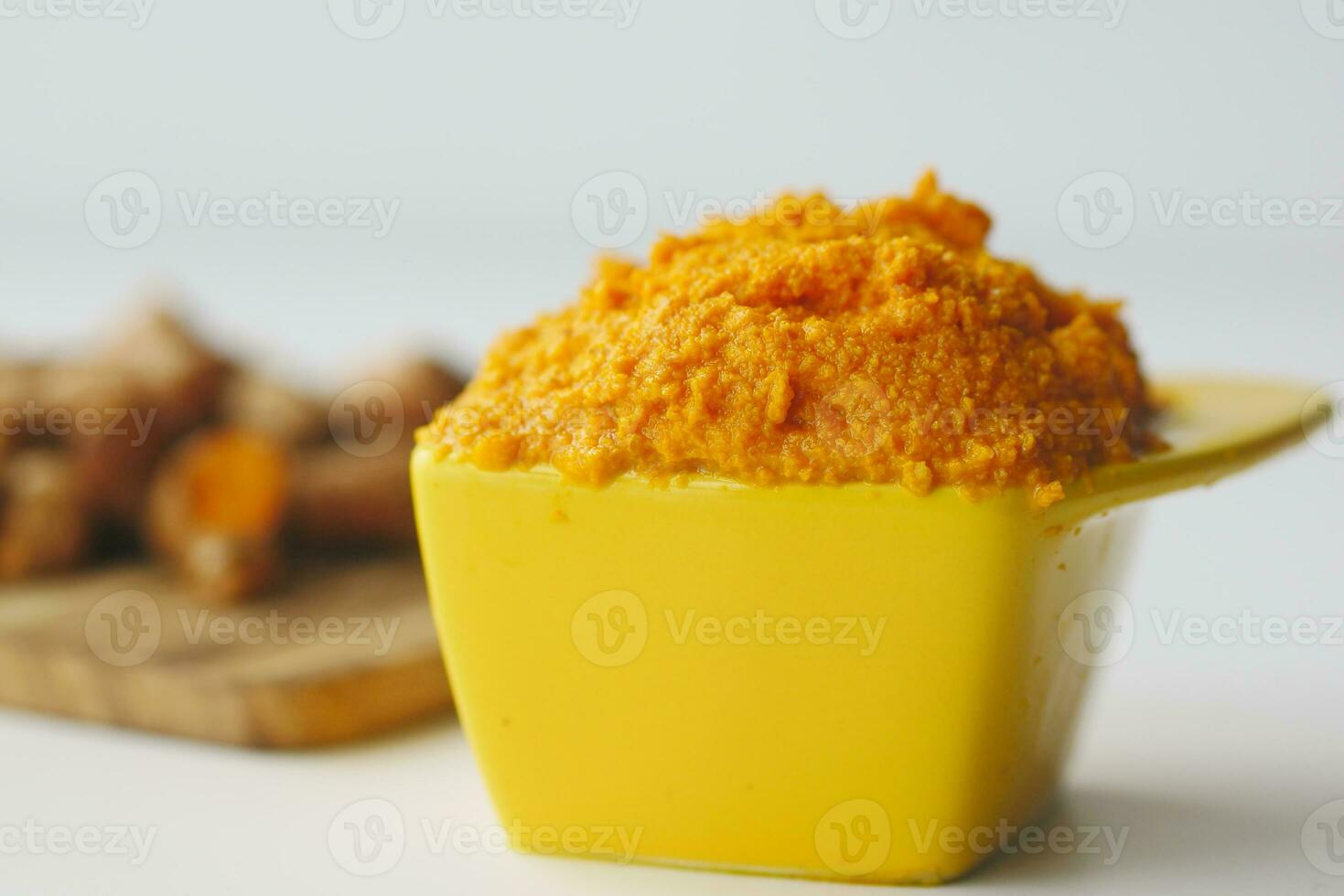turmeric root and paste in a bowl on white background photo