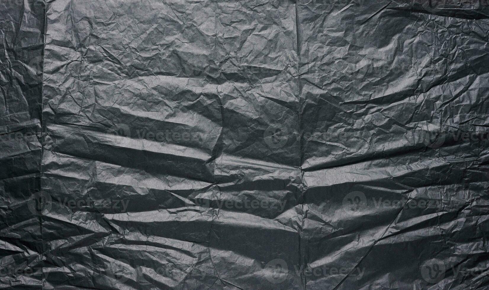 Crumpled sheet of black parchment paper, abstract background photo