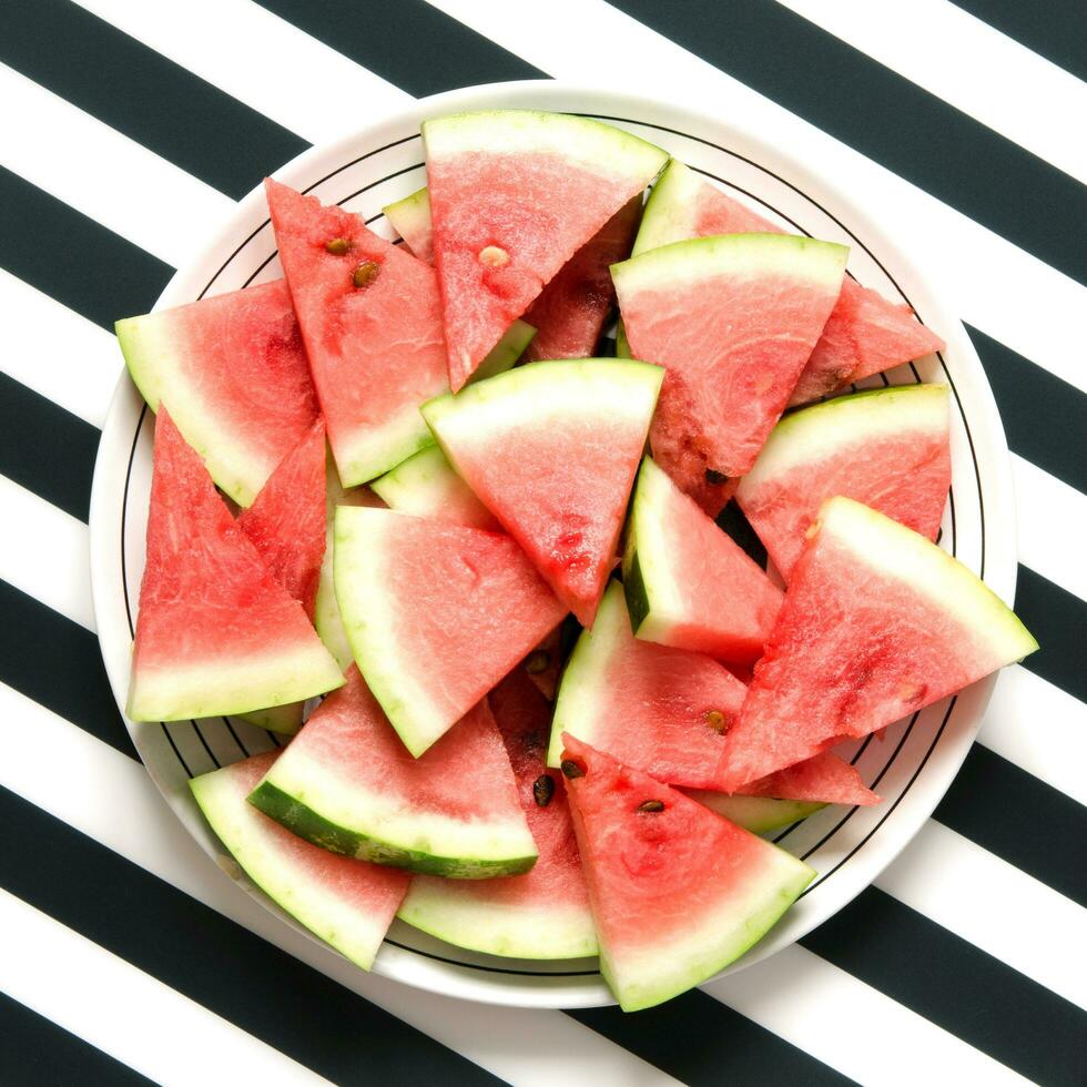Fresh red watermelon slice in plate on striped background. Summer concept. Top view, Flat lay. - Image photo