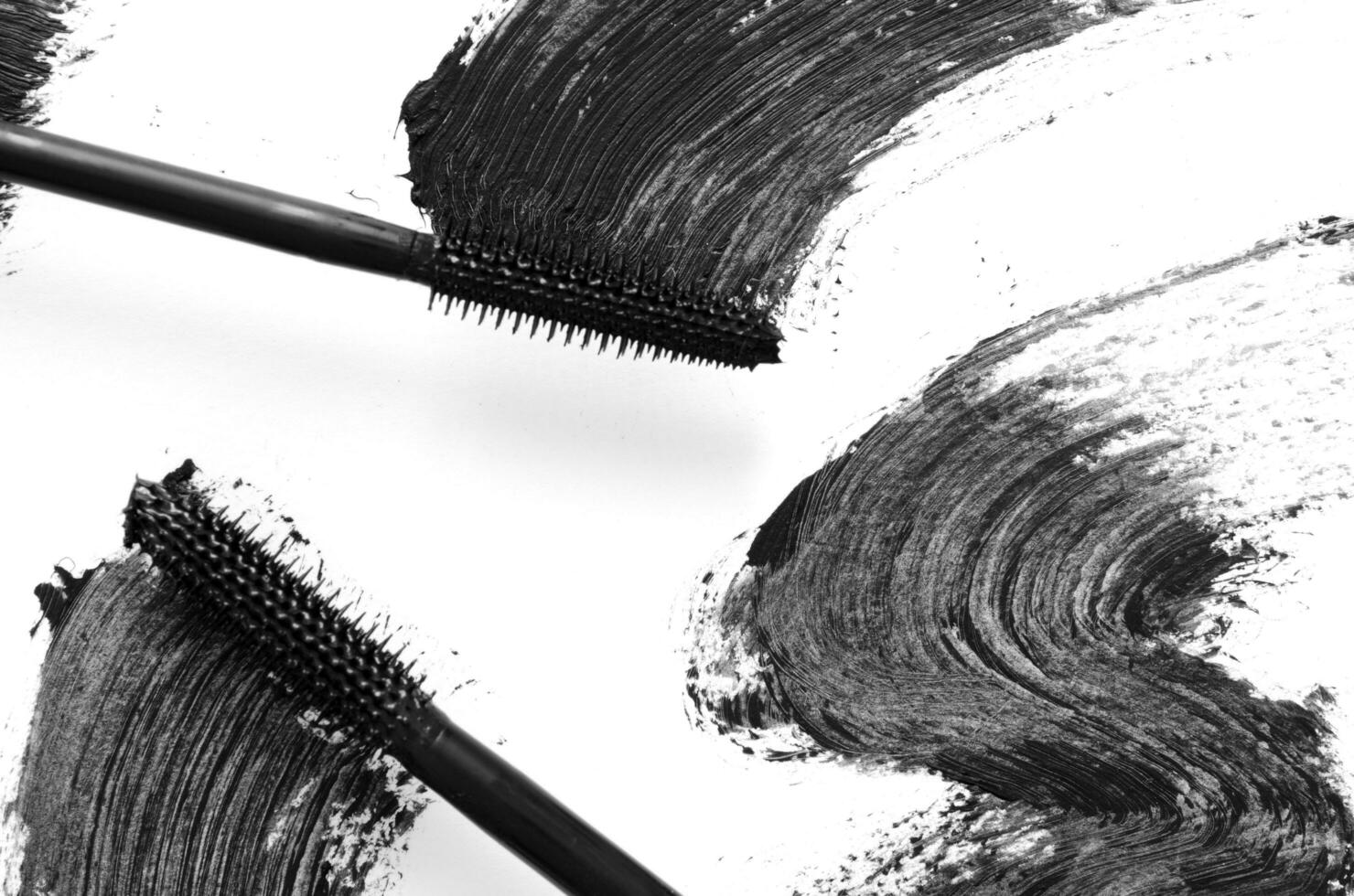 Stroke of black mascara with applicator brush close-up, isolated on white background. - Image photo