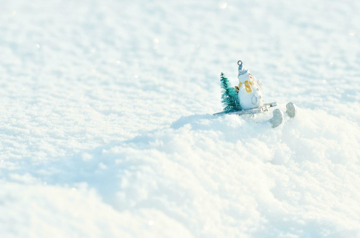 Snowman in a sleigh with a Christmas tree in snowdrifts. Winter season background. photo