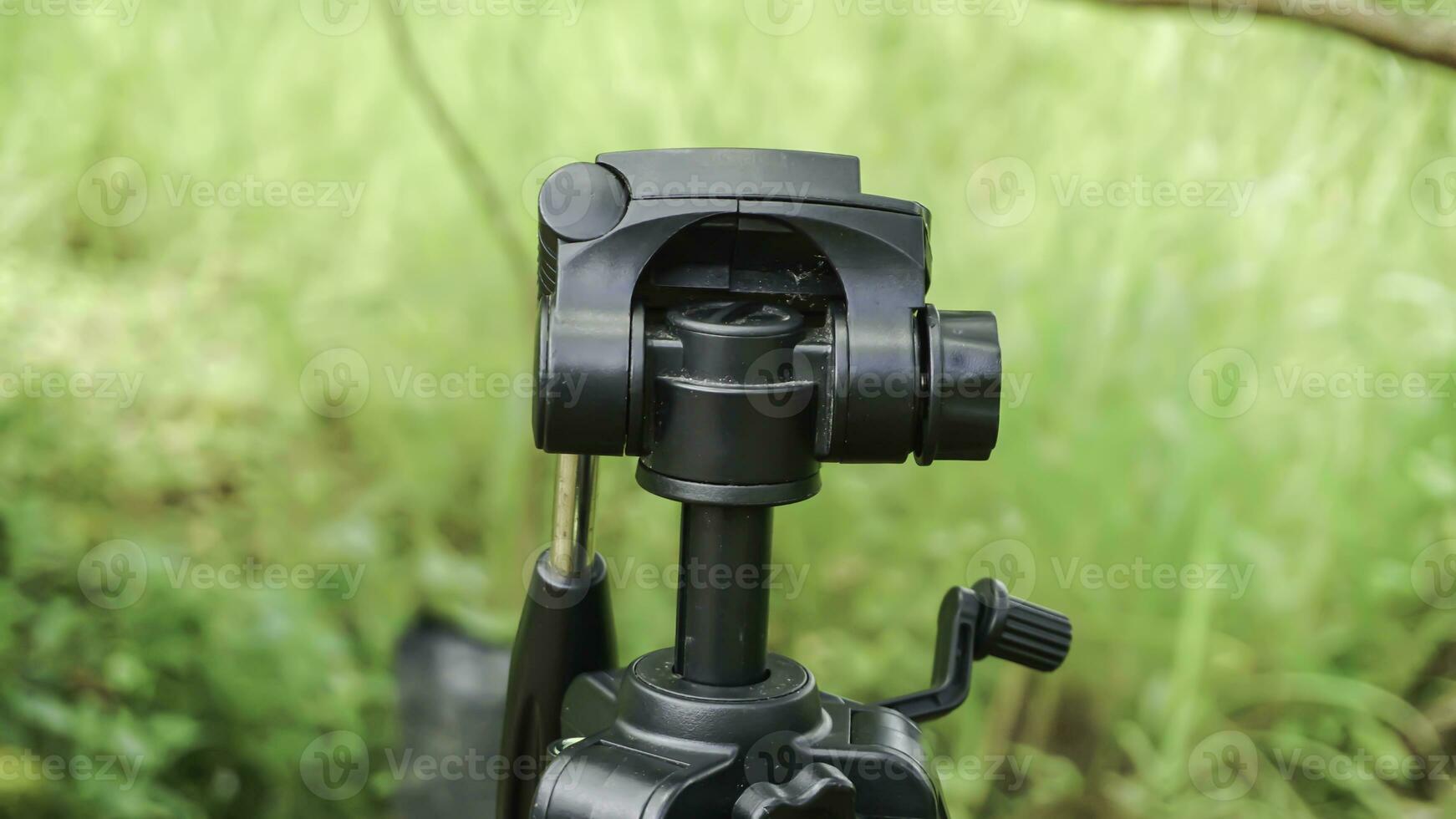 Close-up of a tripod on a blurred background of green grass photo