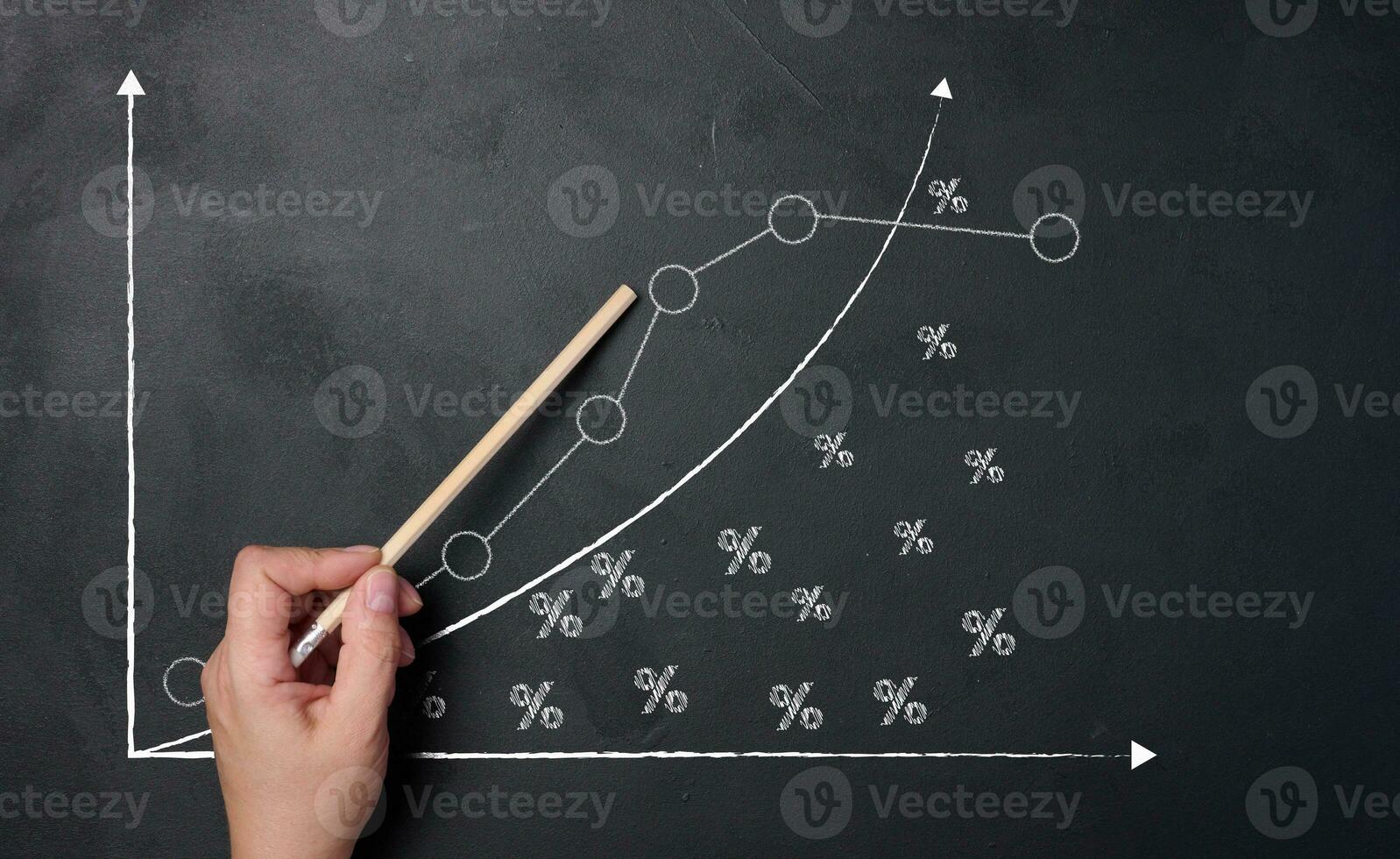 A woman's hand points to a graph with growing indicators drawn on a black chalkboard. photo