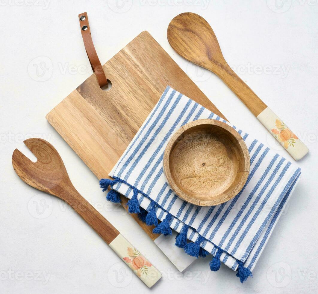 Empty bowl and wooden spoons on a white table, top view photo
