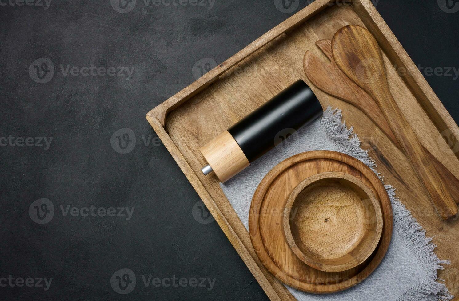 Empty bowl and wooden spoons on a black table, top view photo