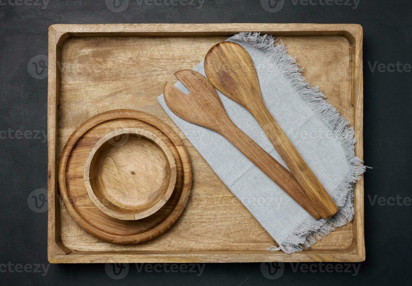 Empty bowl and wooden spoons on a black table, top view photo