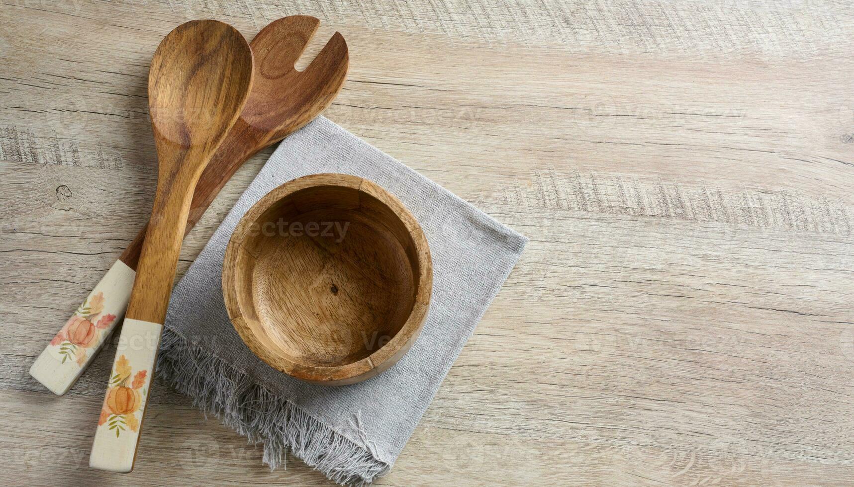 Empty bowl and wooden spoons on a wooden table, top view photo