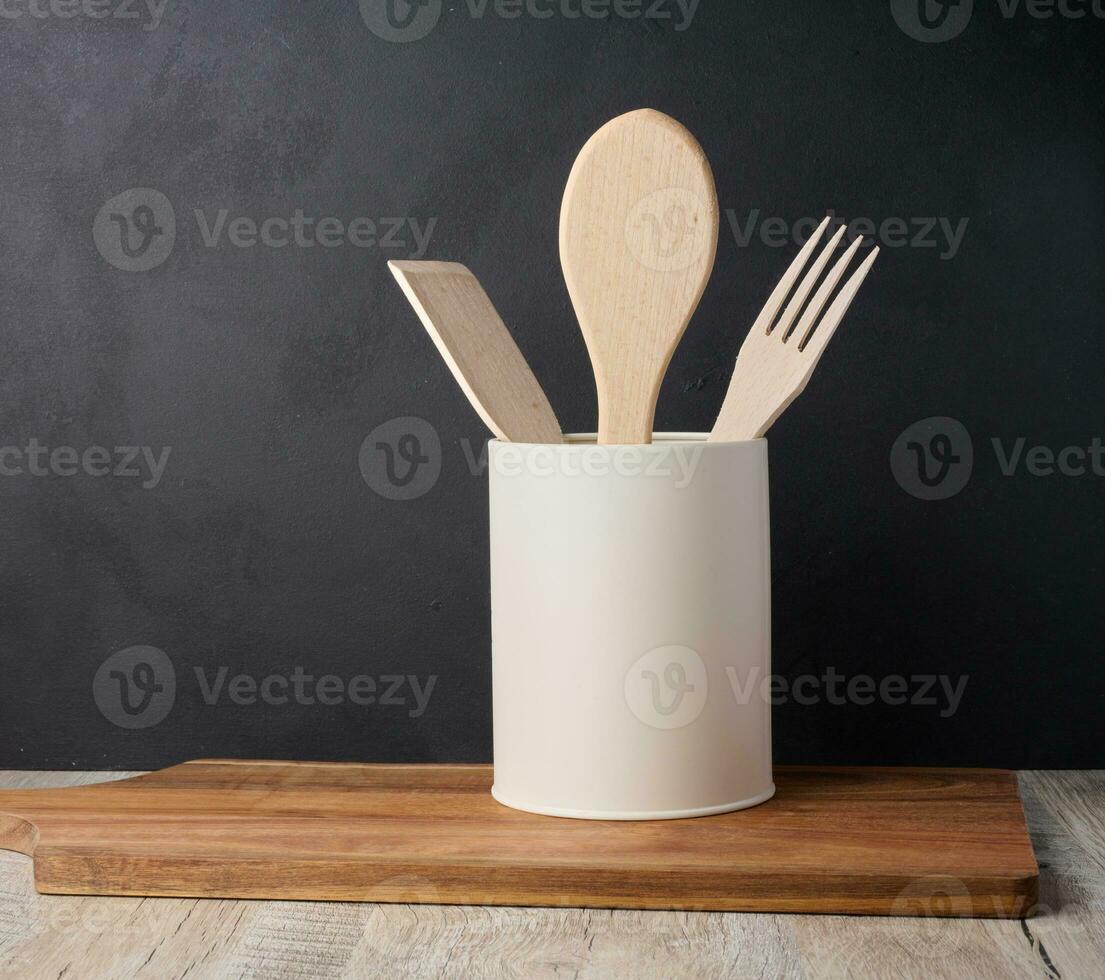 Wooden spoons and forks in a stand on a black background, kitchen utensils photo