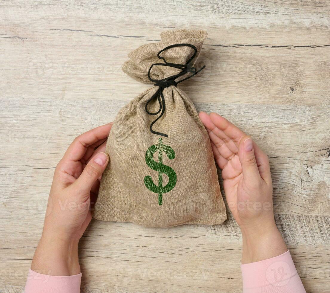 Female hands holding a stuffed canvas bag with a dollar sign, concept of wealth and success photo