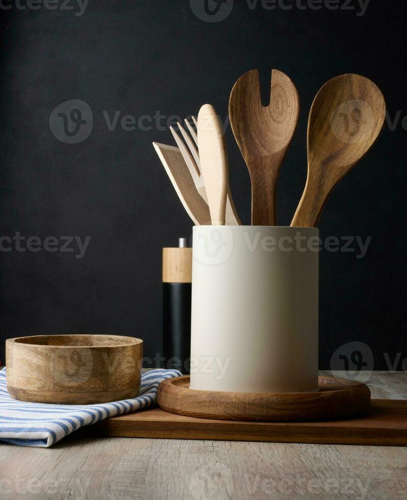 Empty bowl and wooden spoons on a table, black background photo