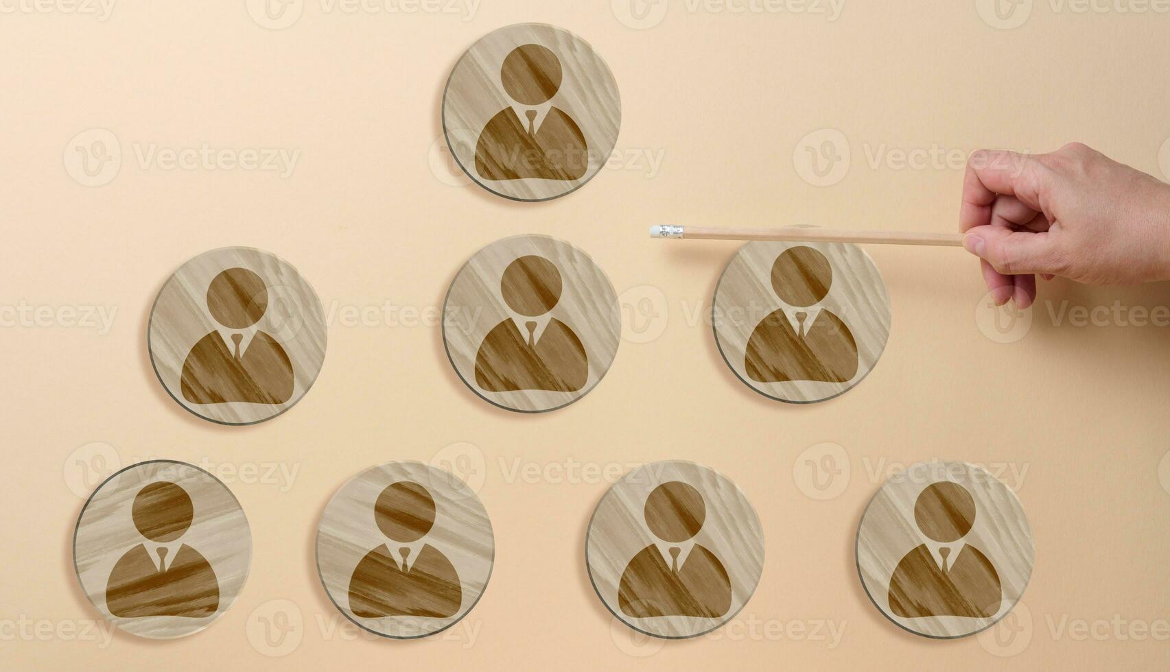 Circular wooden plaques with personnel icons and a hand, representing the concept of organizational structure photo