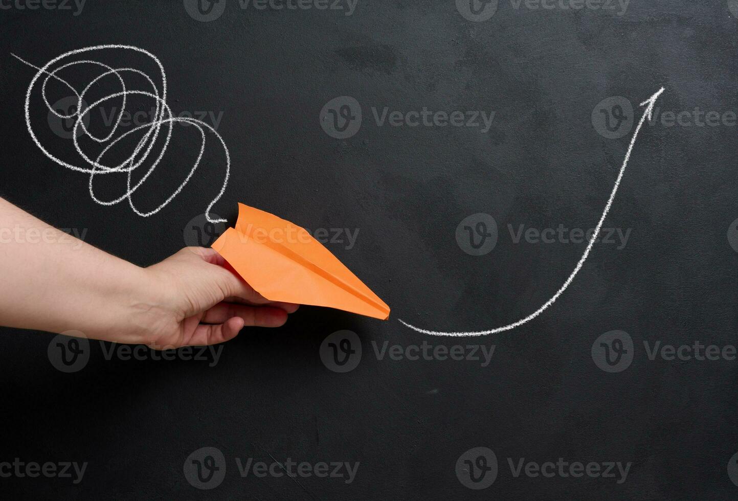 A hand holds a paper airplane with a drawn flight trajectory on the board, representing the concept of support and mentorship, providing assistance photo