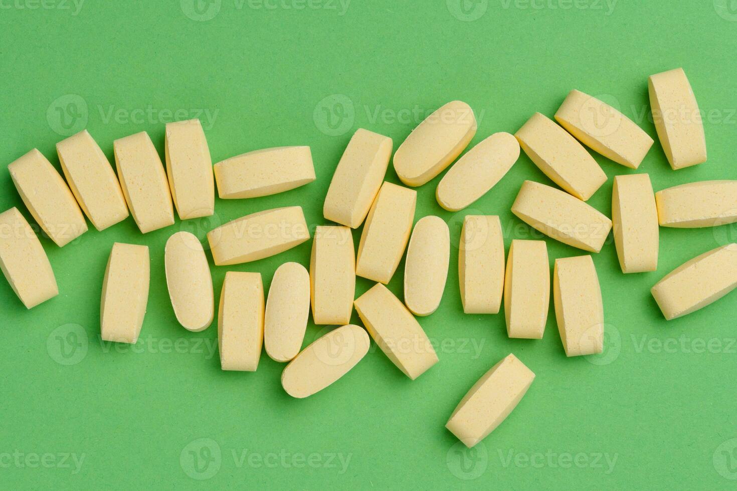 Yellow oval tablets on a green background, top view photo