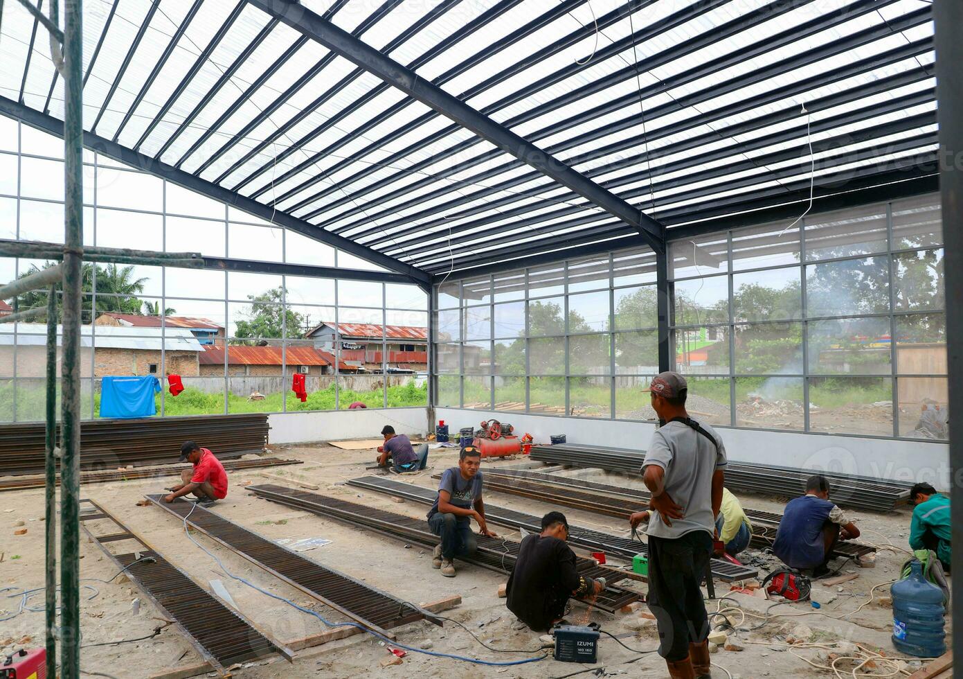 Activities of construction workers at construction site while carrying out welding for roof installation without using helmets and personal protective equipment photo