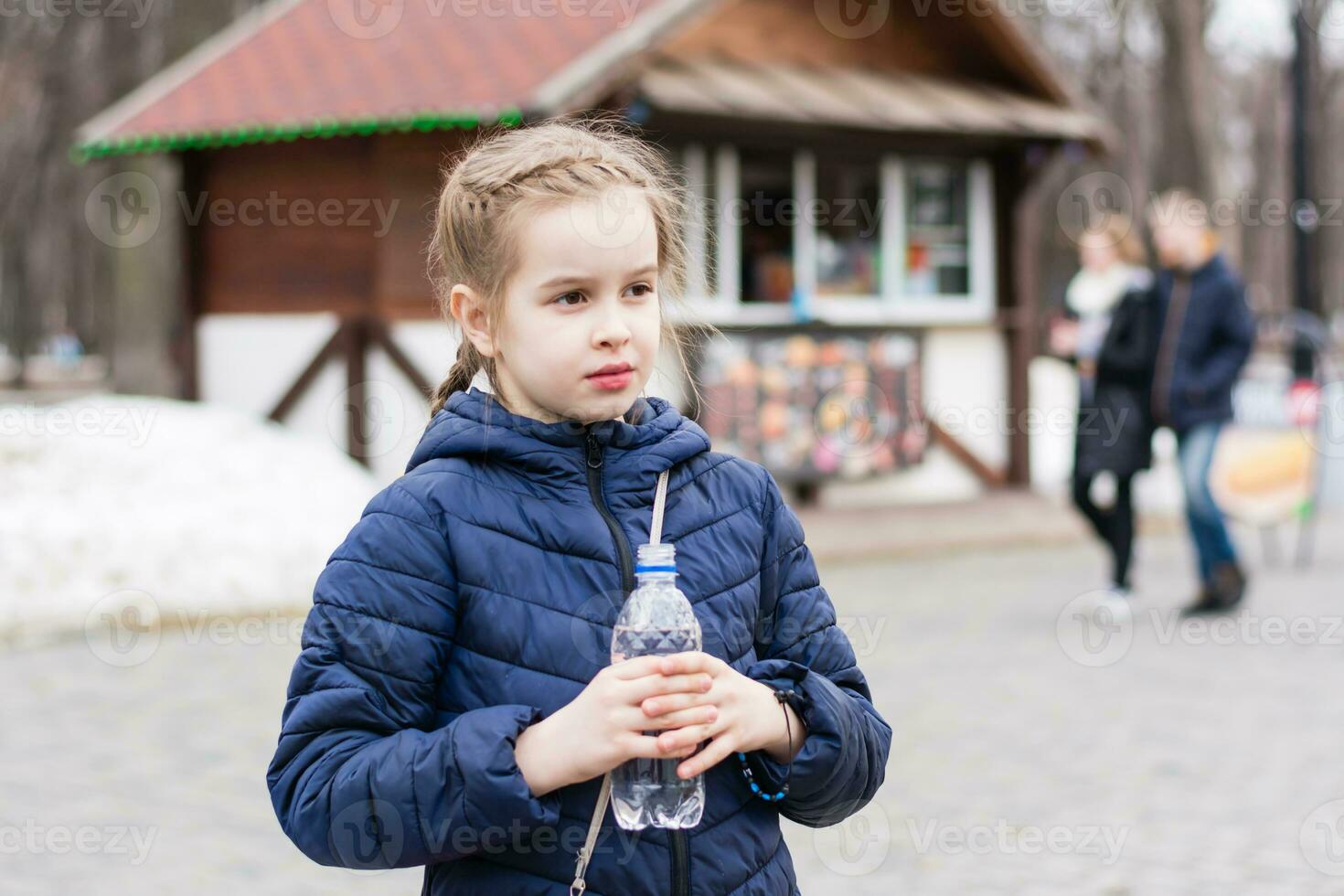 Cute girl holding a bottle with drinking water on the background of a food truck in a city park. Takeaway food photo