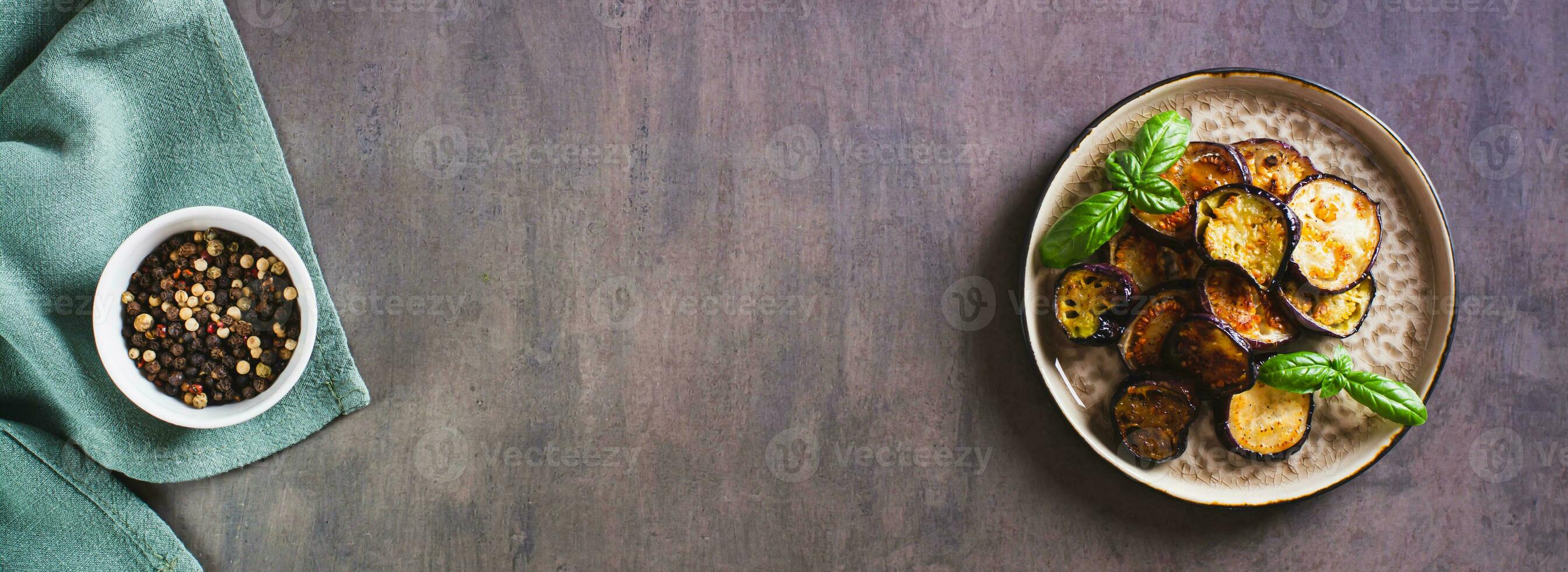 piezas de frito berenjena con especias y albahaca en un plato en el mesa parte superior ver web bandera foto