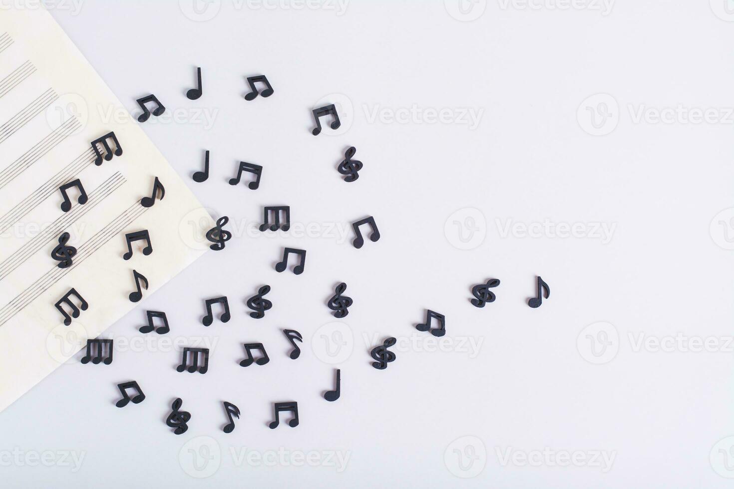 Music sheet and spiral of black musical notes on a light background top view photo