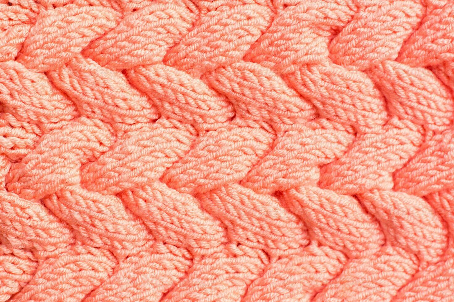 Textured background. Knitted fabric in peach color in the form of intertwined braids. Top view photo