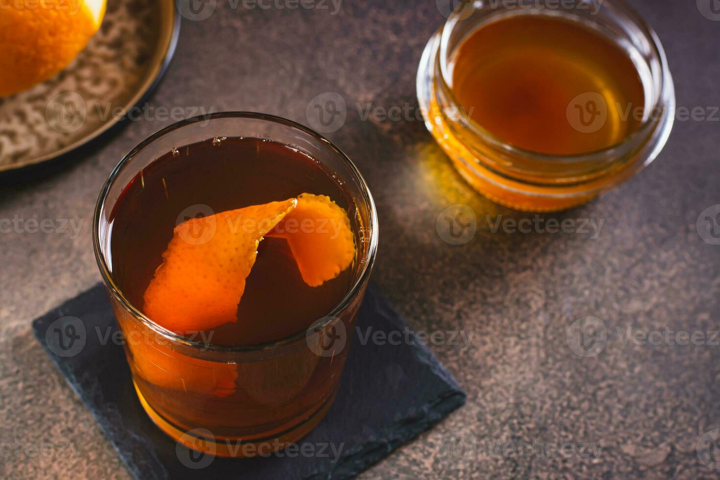Brown butter whiskey cocktail and orange zest in a glass on the table photo