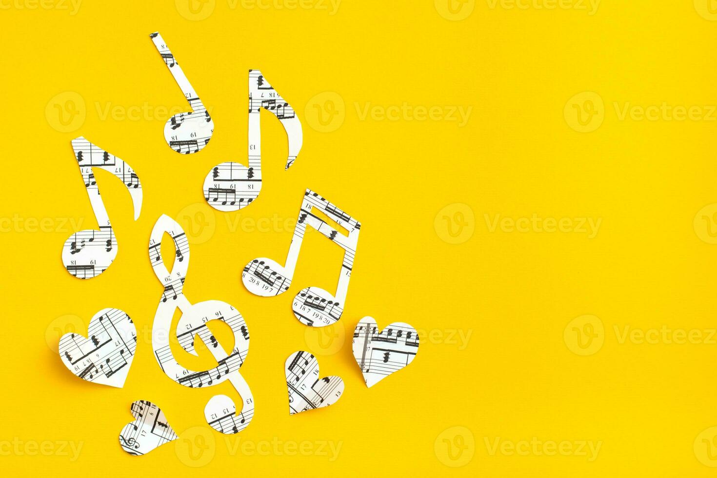 Musical notes, clef and hearts cut from paper with musical text on yellow background. Copy space photo