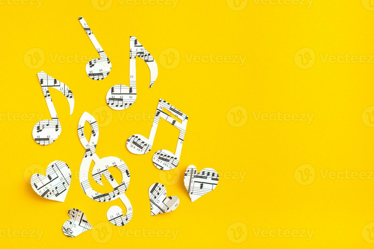 Musical notes, clef and hearts cut from paper with musical text on yellow background. Copy space photo