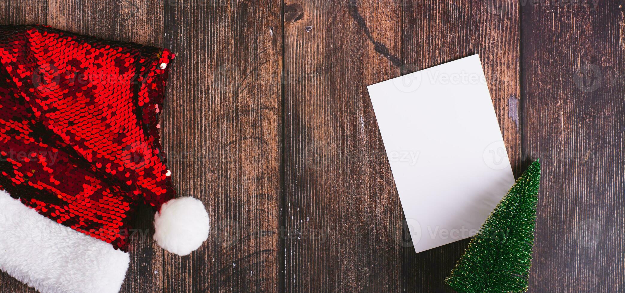 Gift list, christmas tree and santa claus hat on table top view web banner photo