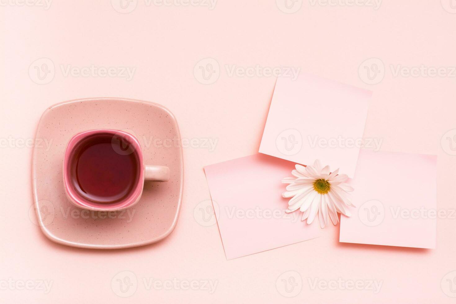 The concept is pink. Pink drink in a coffee cup, leaf for writing and chrysanthemum on a pink background. Top view photo