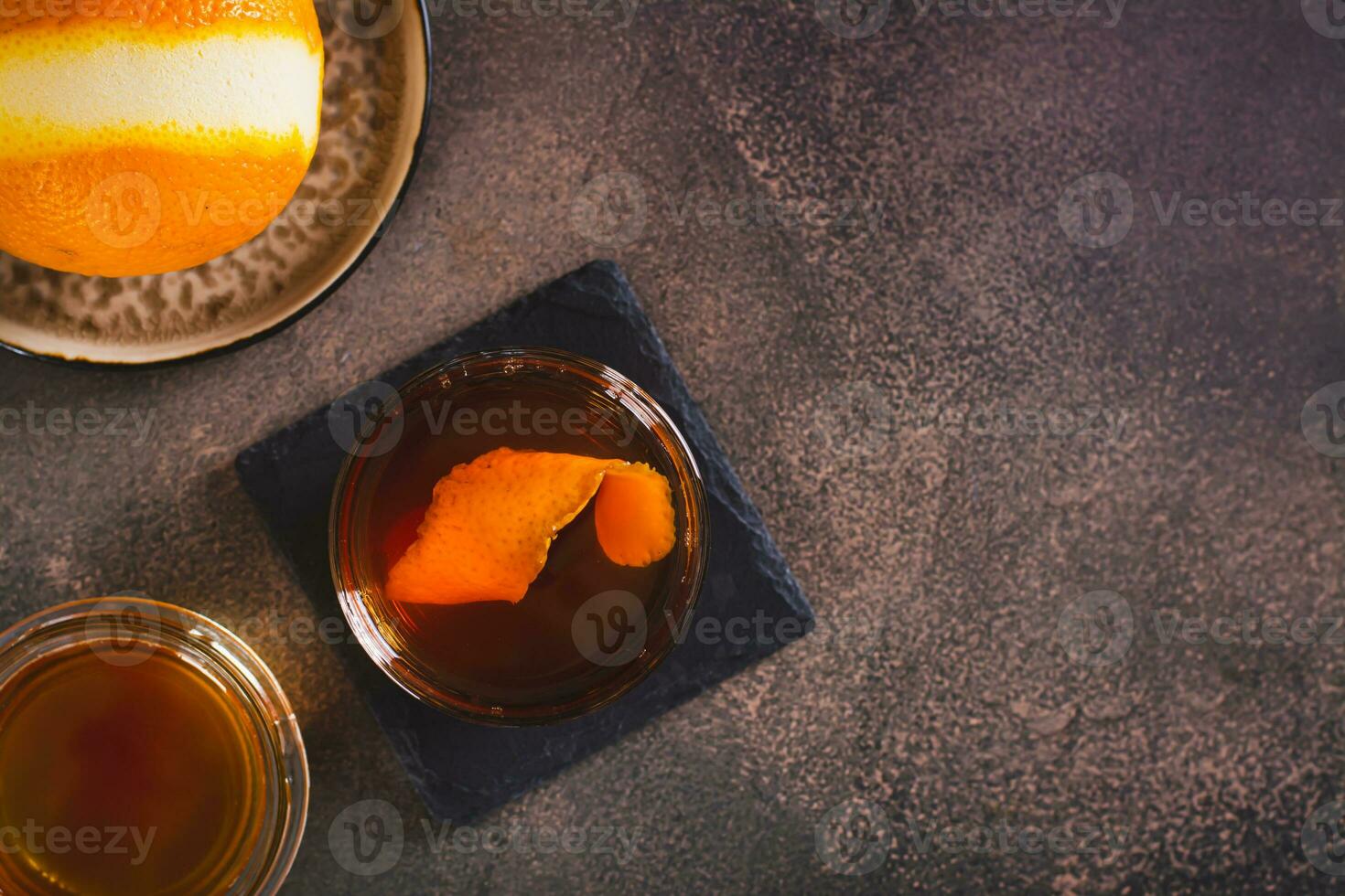 Hard alcoholic brown butter cocktail with orange zest in a glass top view photo