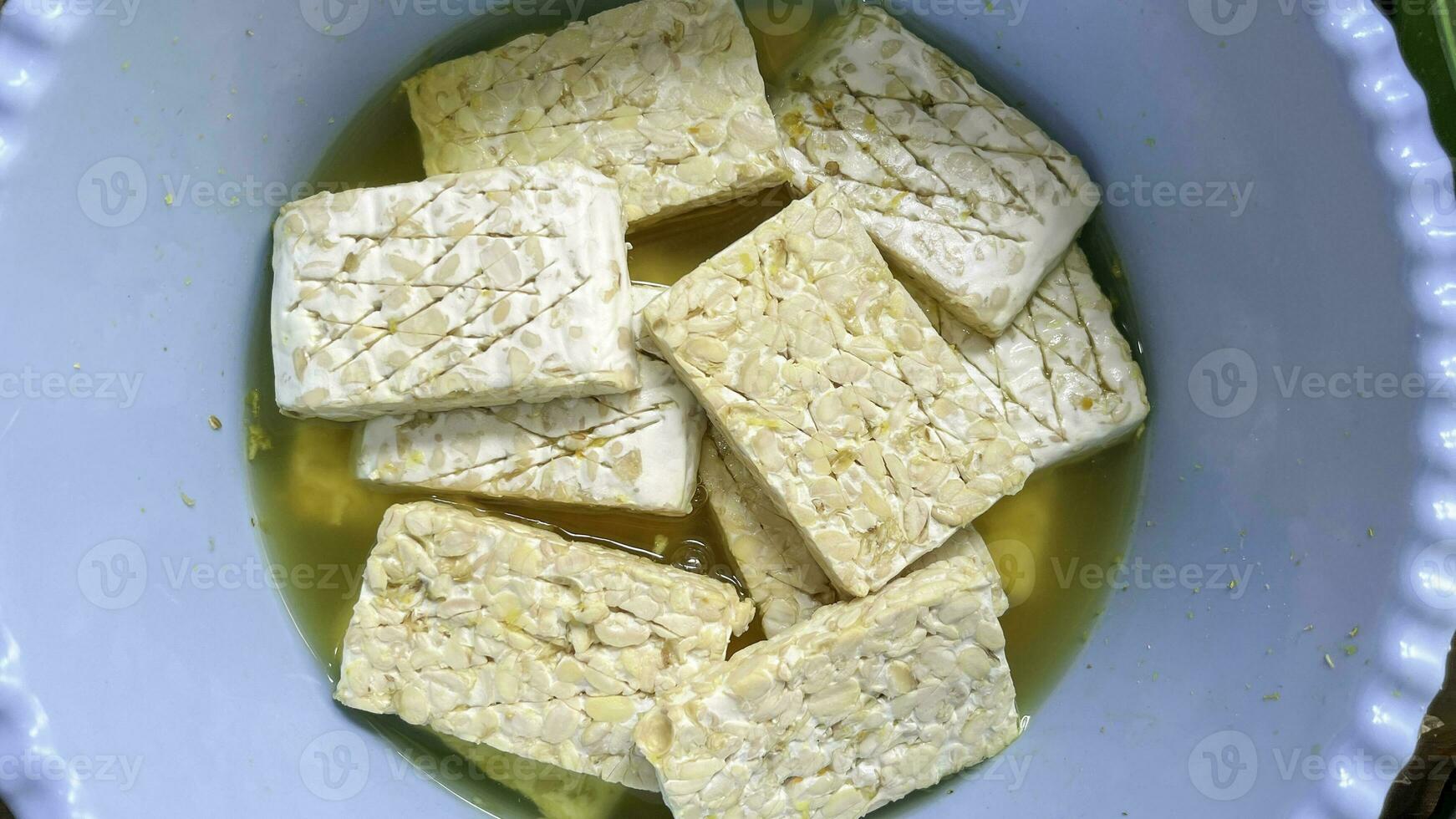 Raw tempeh pieces are soaked in salt and garlic before being fried. Marinate tempeh to add flavour. photo