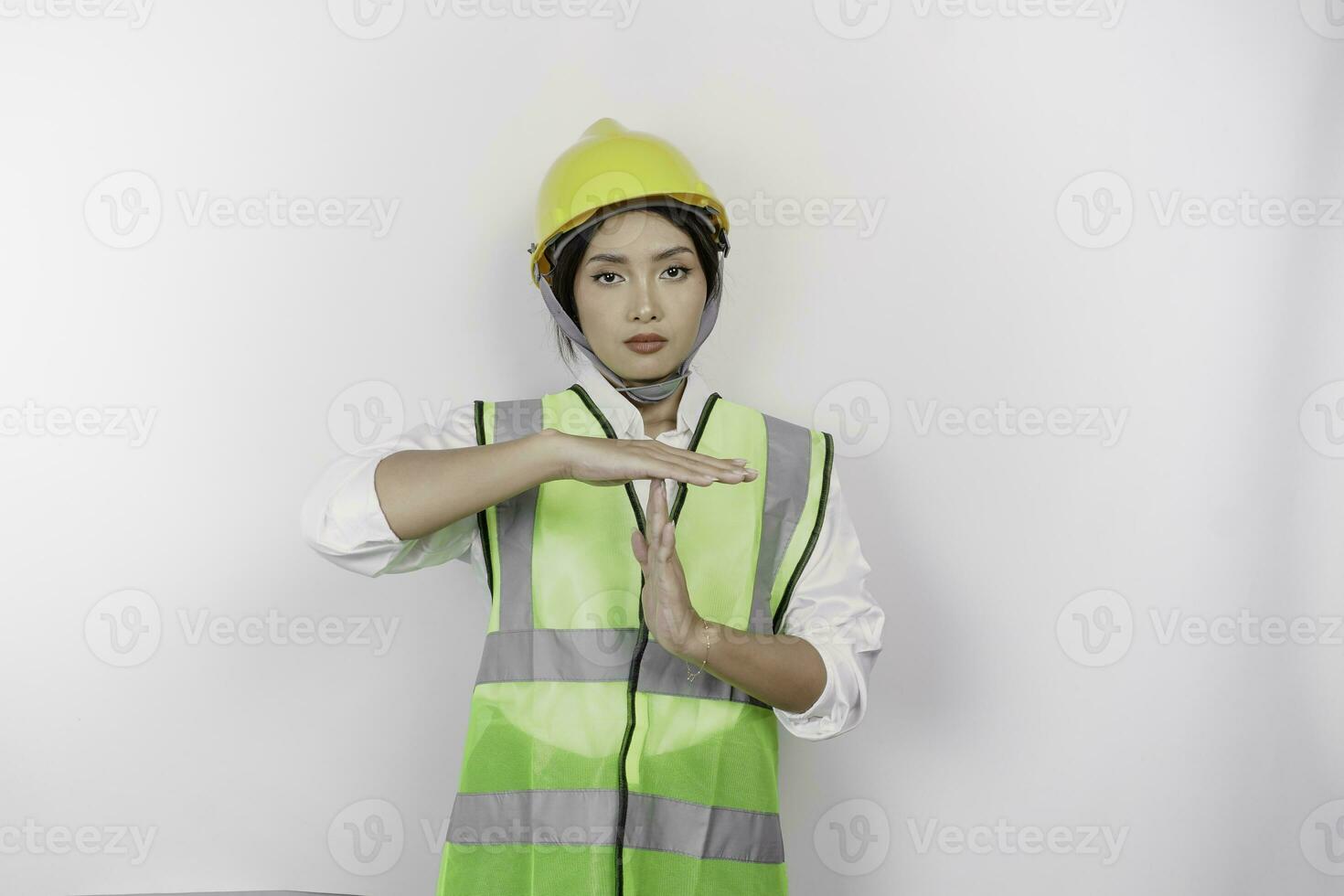 Hispanic woman labor wearing safety helmet and vest doing time out gesture with hands and serious face, isolated white background photo