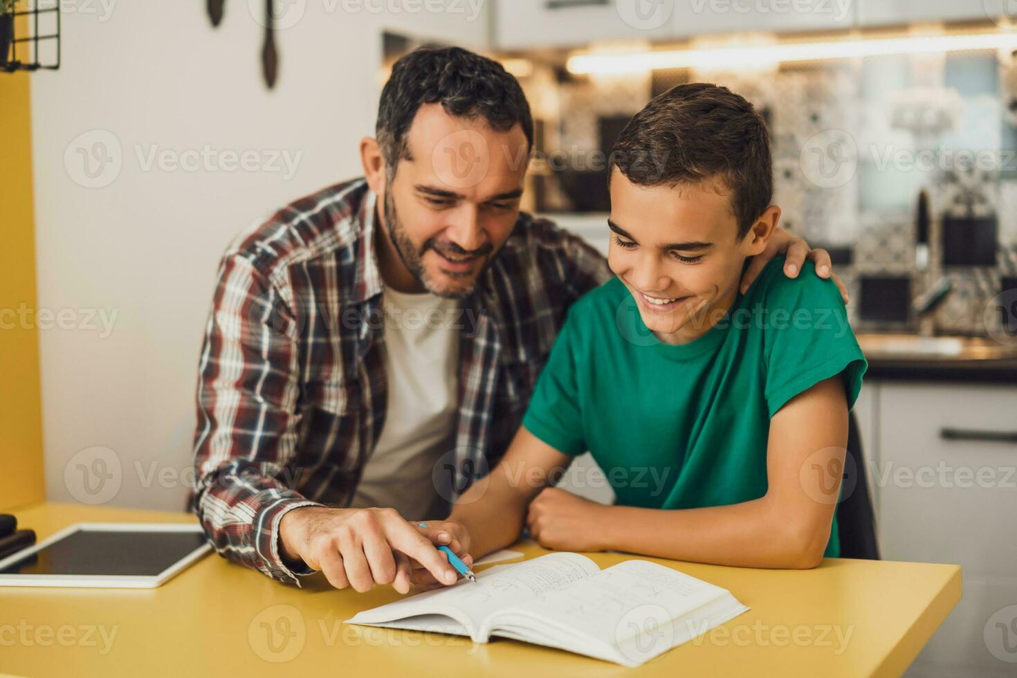 Father is helping his son with learning. They are doing homework together. photo