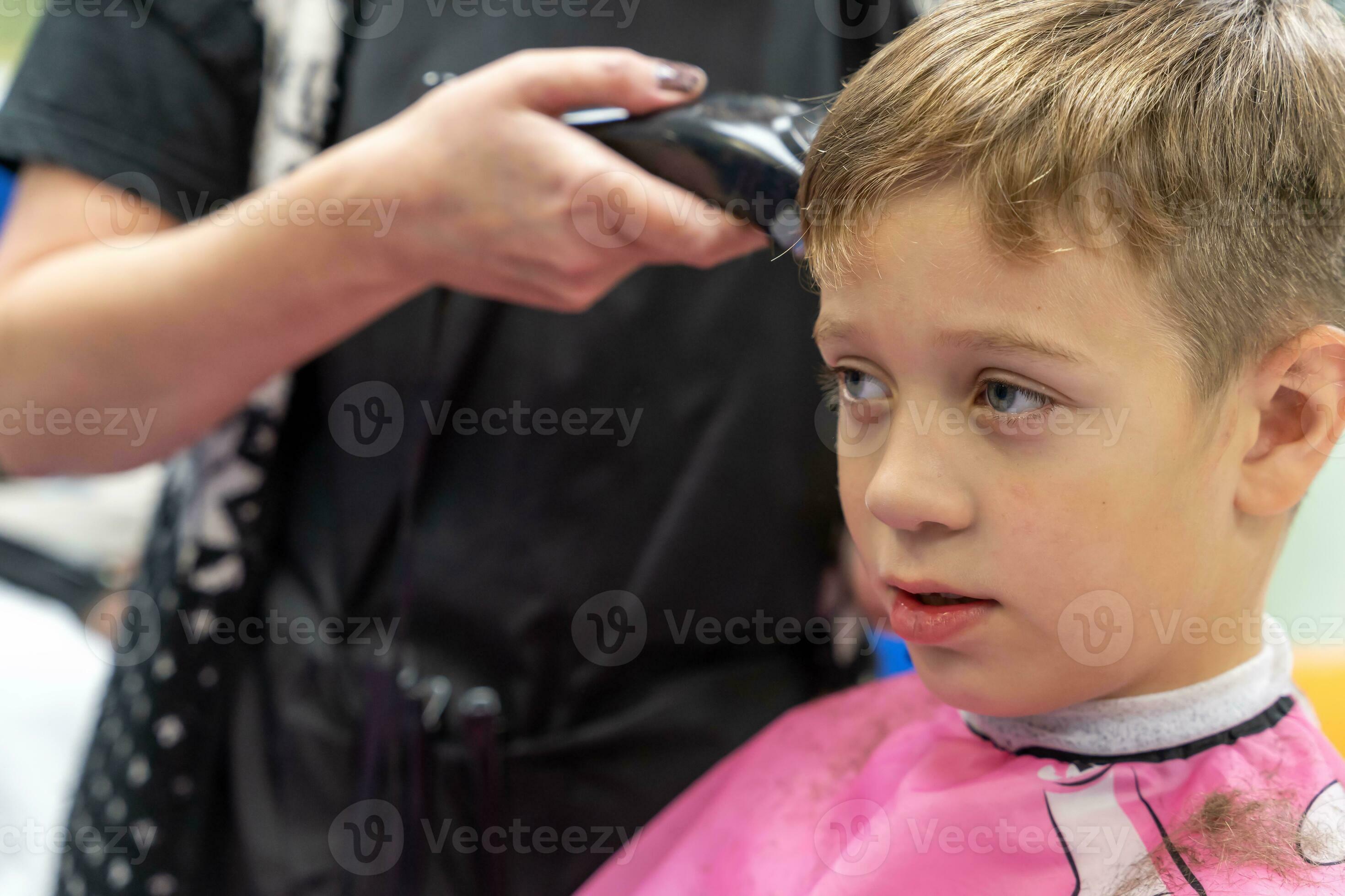 Hair cutting for a child using a hair clipper in a beauty salon