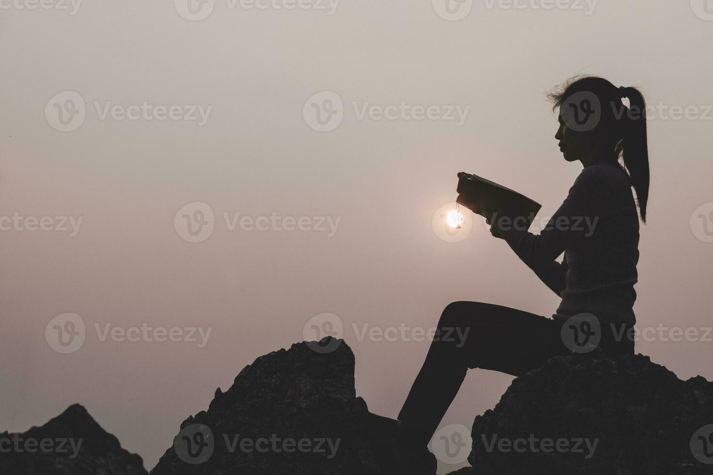 Women standing holding holy  bible for worshipping God at sunset background, Pray to the god, christian silhouette concept. photo