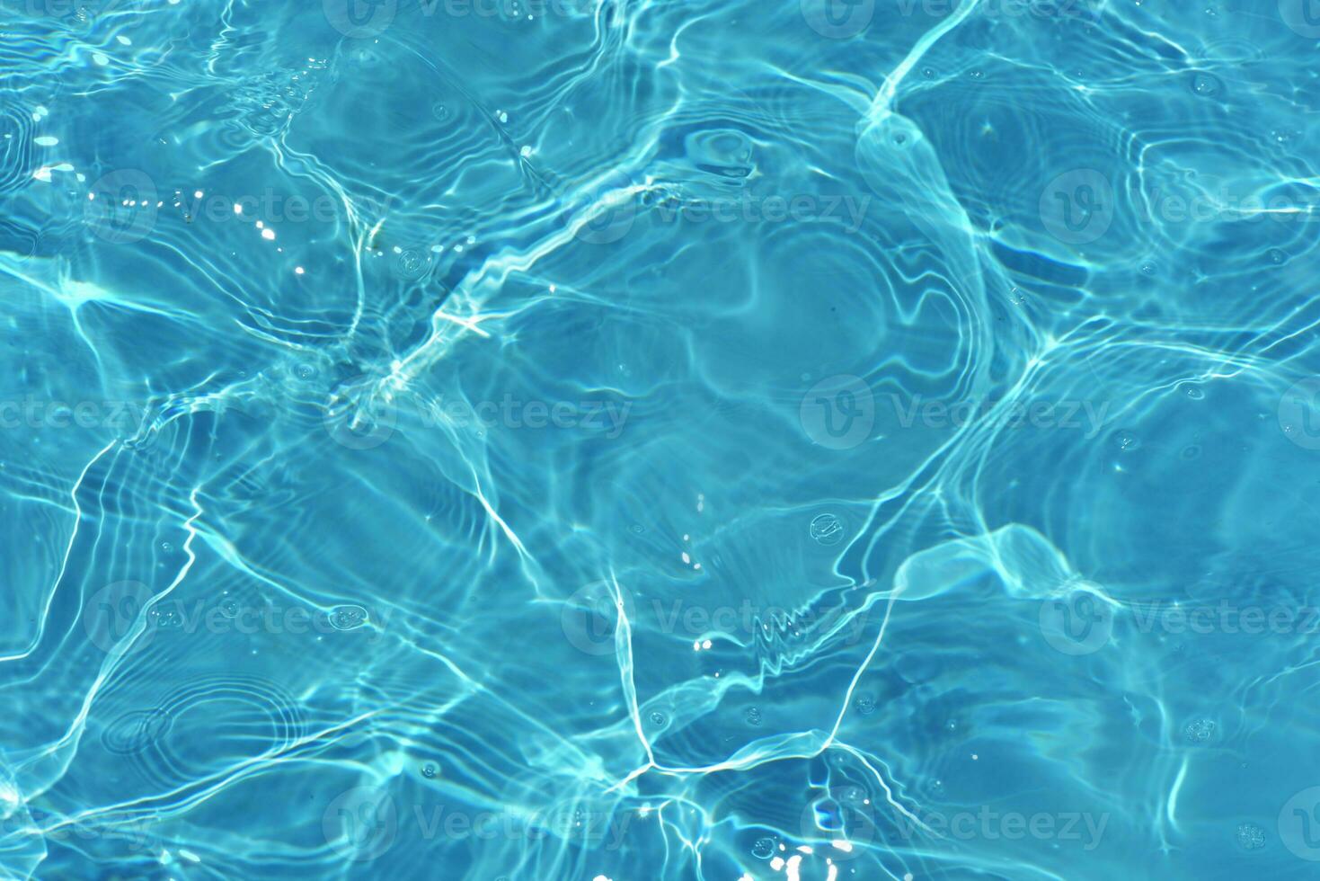 Blue water with ripples on the surface. Defocus blurred transparent blue colored clear calm water surface texture with splashes and bubbles. Water waves with shining pattern texture background. photo