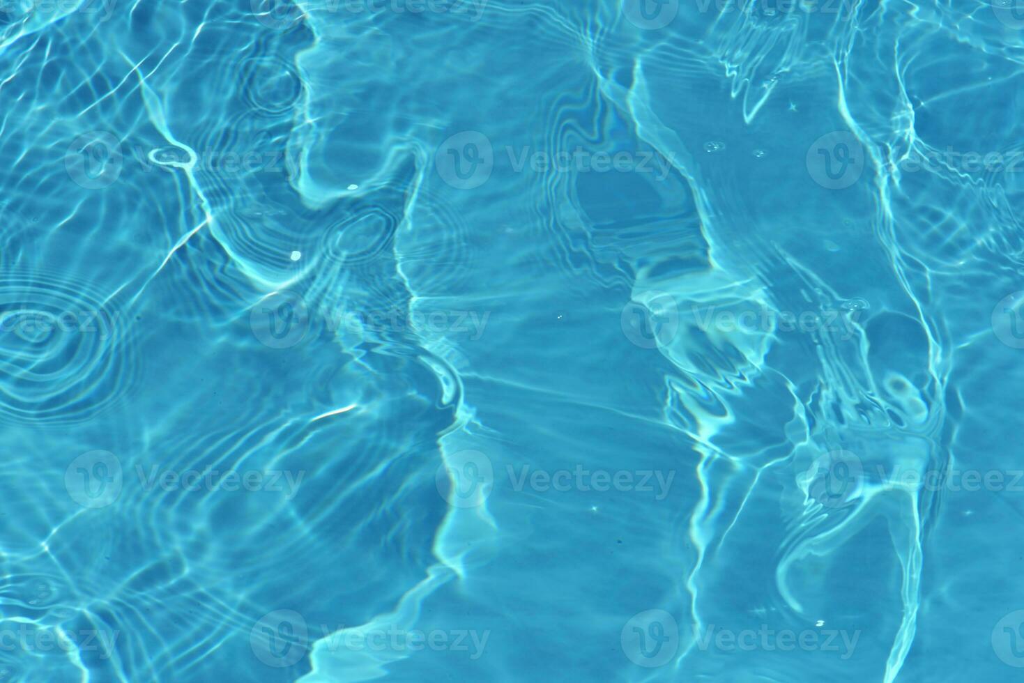 Blue water with ripples on the surface. Defocus blurred transparent blue colored clear calm water surface texture with splashes and bubbles. Water waves with shining pattern texture background. photo
