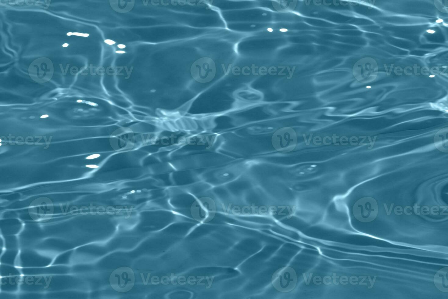 Blue water with ripples on the surface. Defocus blurred transparent blue colored clear calm water surface texture with splashes and bubbles. Water waves with shining pattern texture background. photo