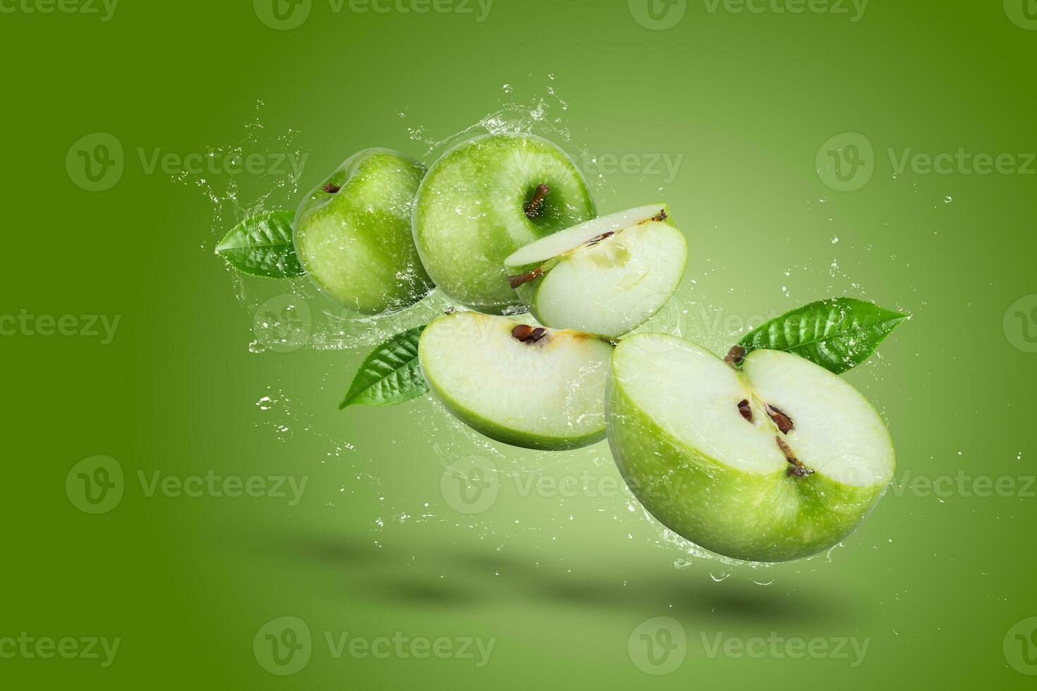 Water Splashing on Green apple and cut slice with seed on green background. photo