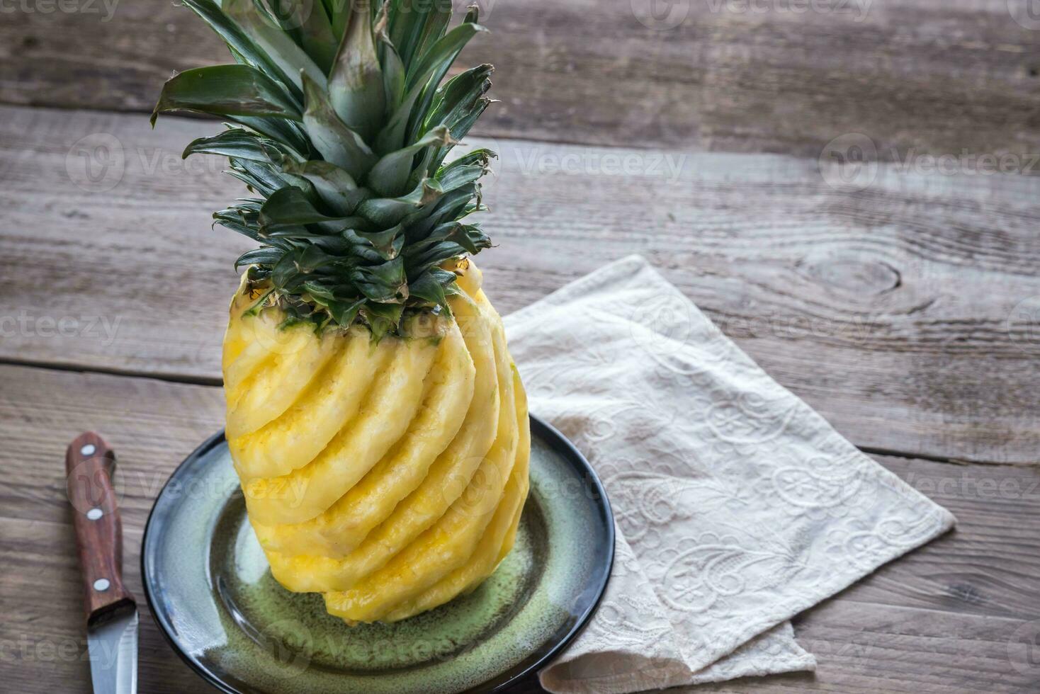 Pineapple on the plate on the wooden background photo