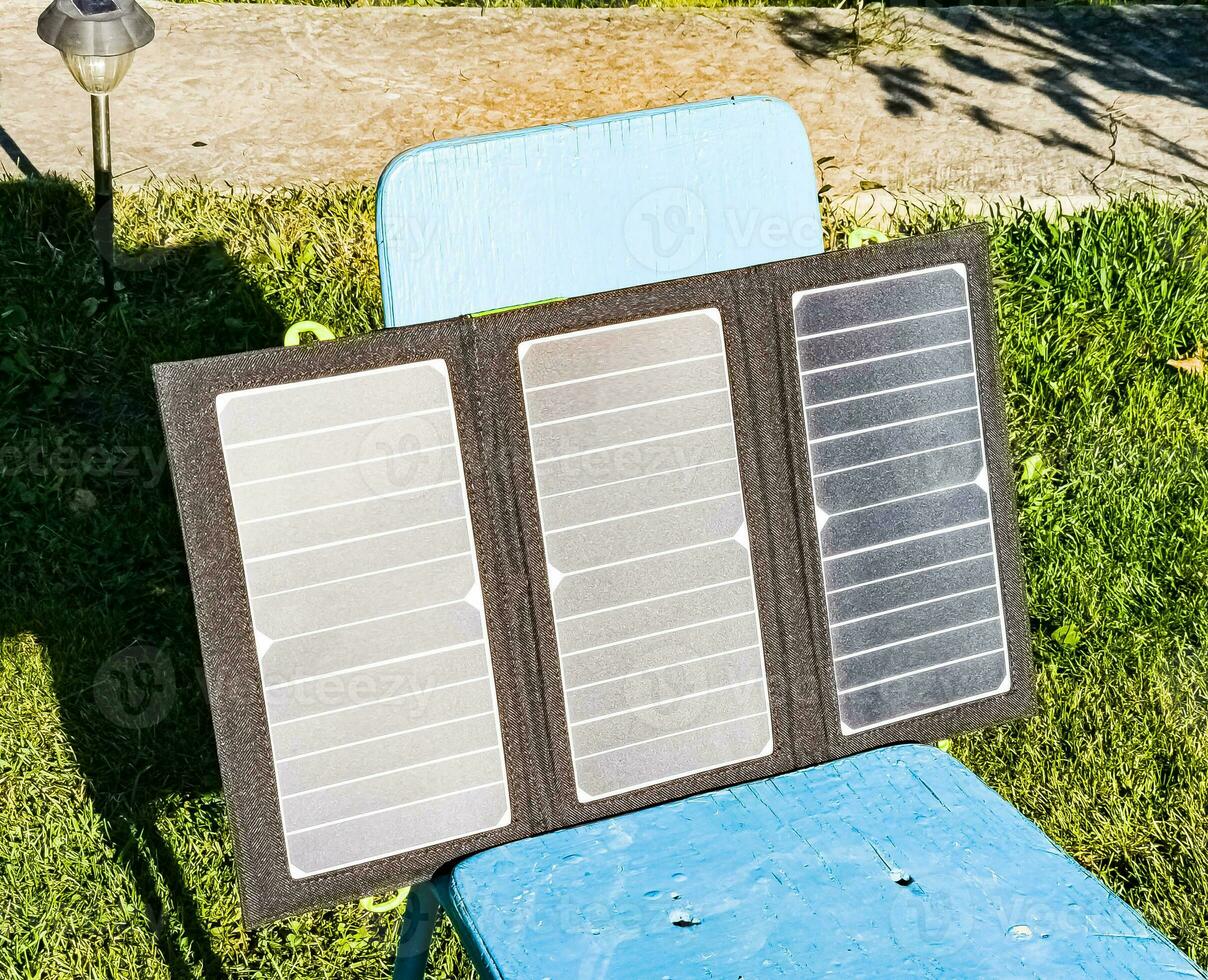 Charging a portable solar battery from the sun at a summer camping site. Clean energy for camp use. photo