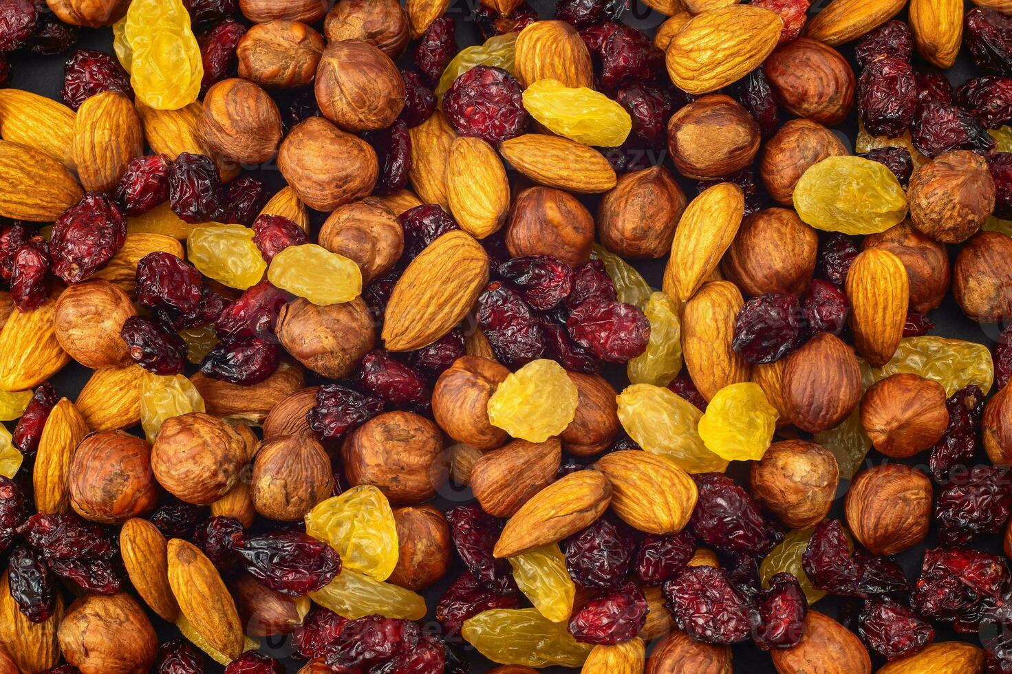 Mixed dried fruits background. Healthy snacks. Almonds, raisins, hazelnuts, cranberries. Assorted nuts and dried berries. View from above. Stack. Healthy food concept photo