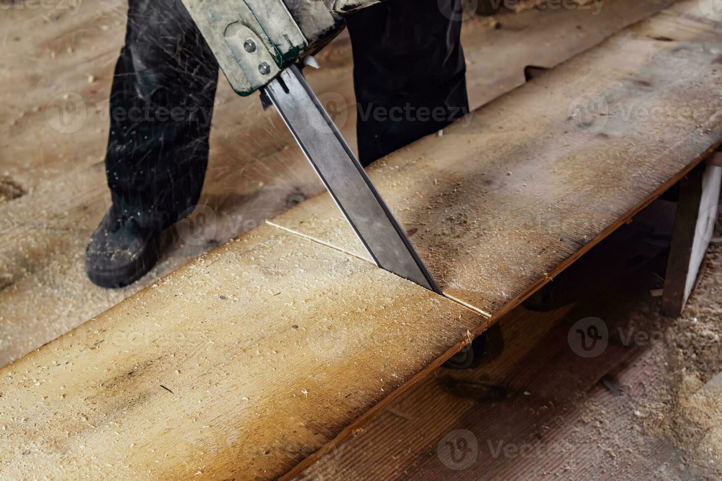 carpintero es aserradura un de madera tablero con un eléctrico sierra. volador astillas antiguo pueblo carpintería taller. foto