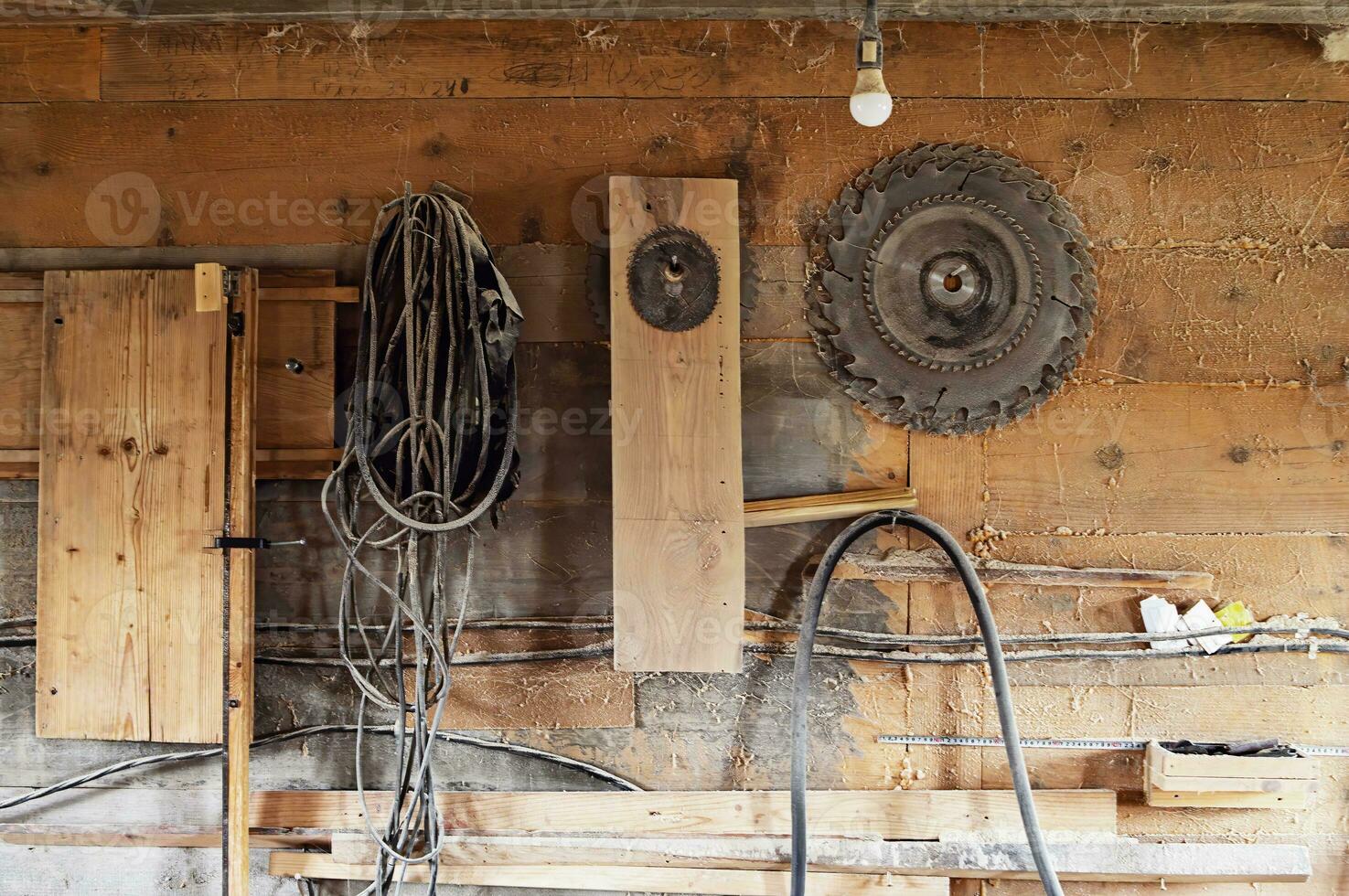 Wall in the carpentry workshop with many tools and planks of wood, as well as some hand tools. Rustic workshop.set of circular saw photo