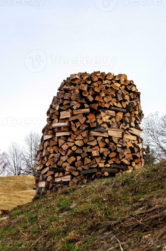 Chopped firewood for kindling and heating the house. pile of firewood, stacked in a circle, a well. Timber harvesting. Rural areas. photo