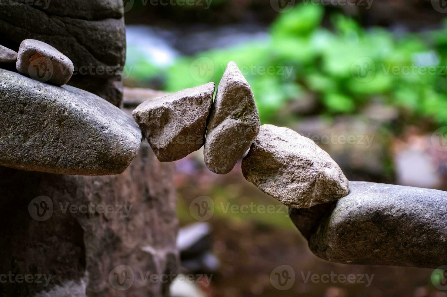 Rock bridge, pyramid, rock balancing art. Close-up of a stack of stones in perfect balance in a mountain forest. Sun rays. Meditation, balance, peace. Hobby. photo
