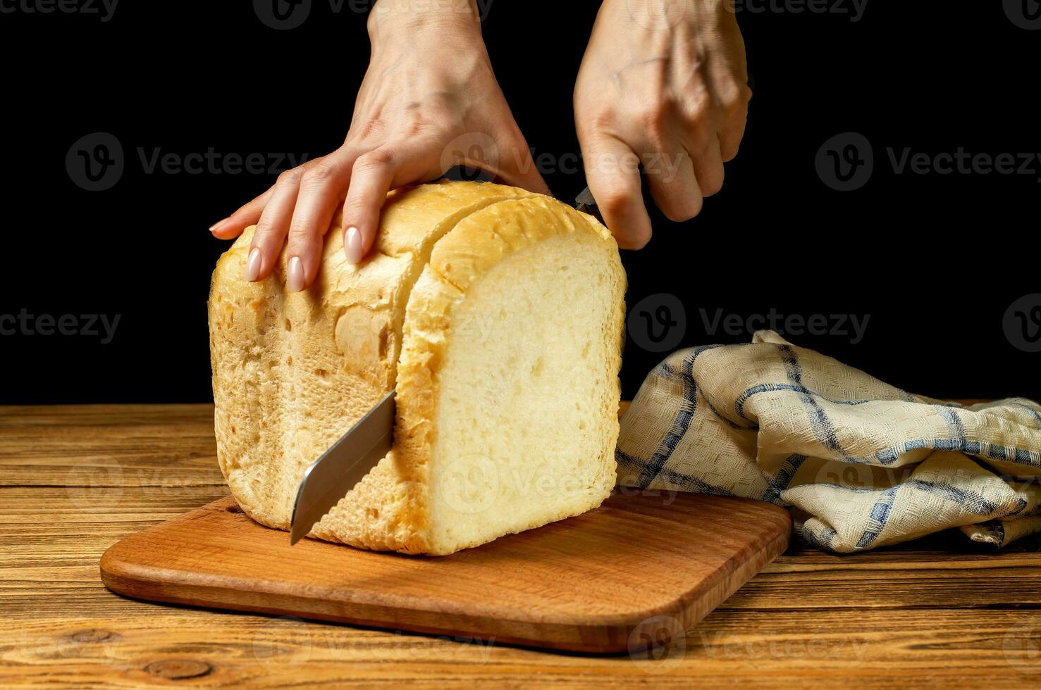 hembra manos corte Fresco blanco hecho en casa un pan en un de madera tablero en un de madera mesa. hecho en casa pasteles, pasteles foto