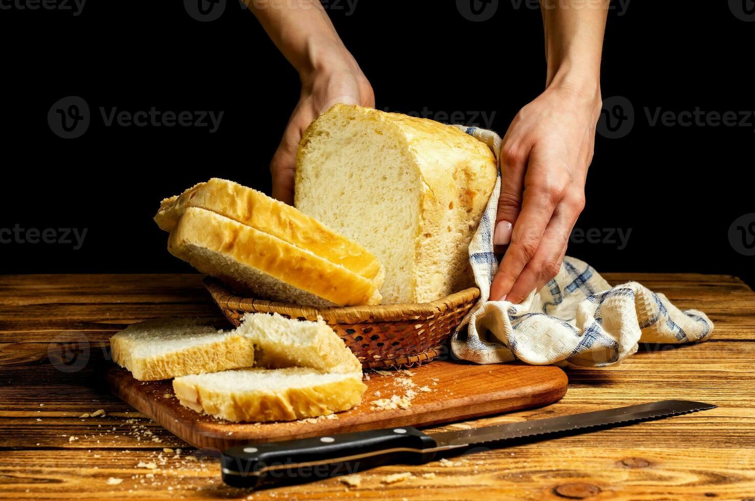 Female hands serving fresh white homemade bread in a basket on a wooden table. Homemade cakes, pastries. photo