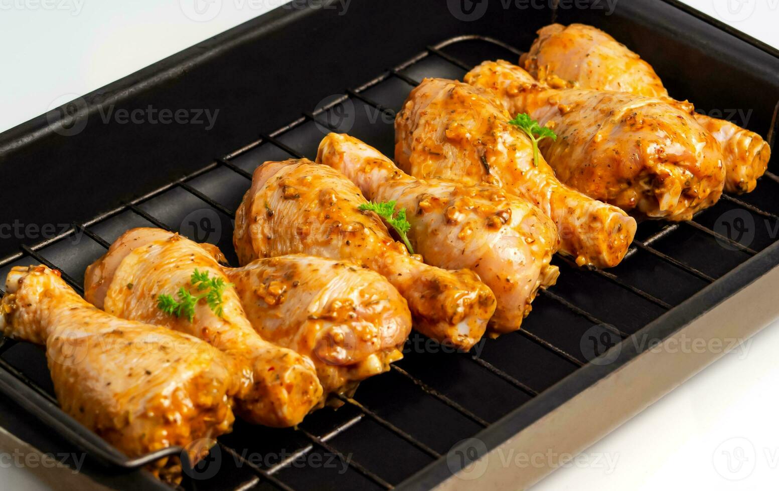 Raw chicken drumsticks marinated red with turmeric, garlic, mustard and parsley. Lined with chicken on a wire rack, ready to bake. B-B-Q. Home kitchen. Side view. photo