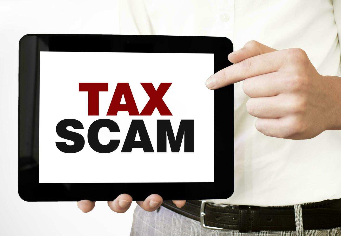 Text TAX SCAM on tablet display in businessman hands on the white background. Business concept photo