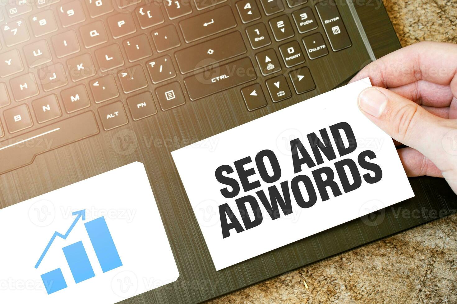 Calculator, red notepad, three colour pencils, silver pen and brown notebook with text SEO AND ADWORDS photo