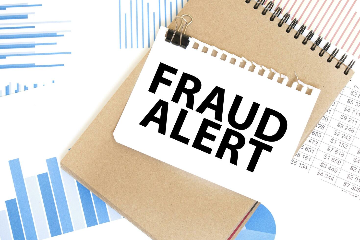 Text fraud alert on white paper sheet and brown paper notepad on the table with diagram. Business concept photo